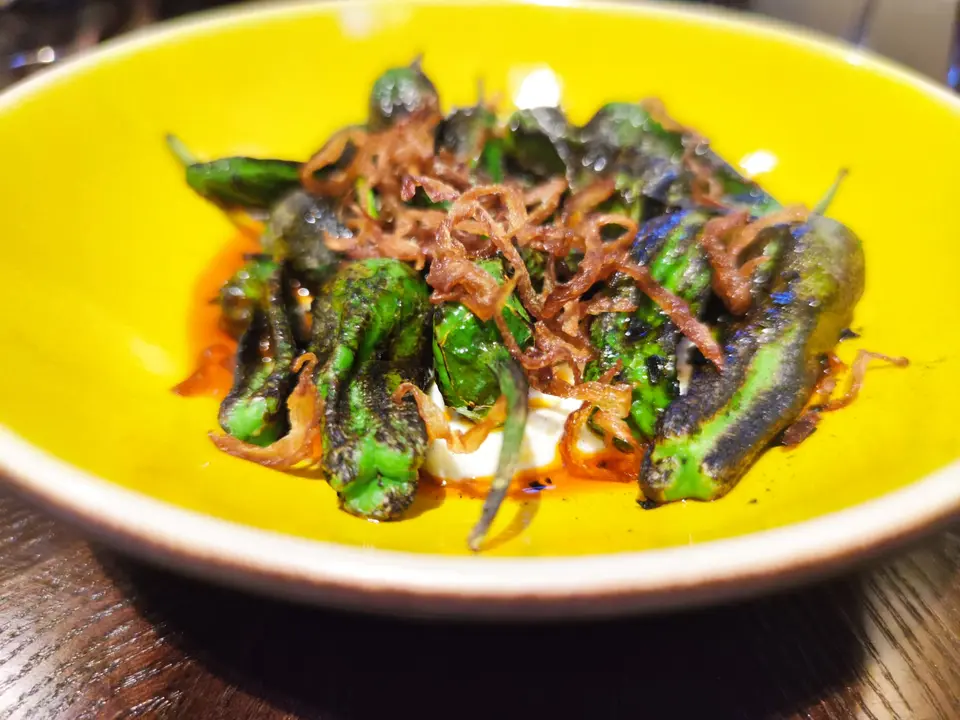 Pimientos de padr&oacute;n asados, queso blando de 
cardamomo verde, aceite de chili Naga.