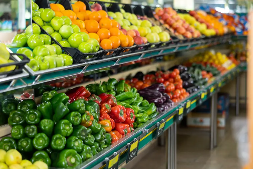 Stand of boxes full of fresh colorful fruits and vegetables in big grocery store